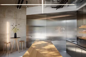 A modern dining room with a wooden table and chairs, surrounded by clean lines and minimalistic decoration, with warm lighting creating a cozy atmosphere