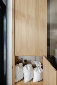 A wooden kitchen cabinet with a brown door and several bags inside, creating an organized and functional storage space