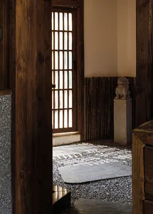 Cozy Asian-style living area with wooden walls and floors, a rug, and a door with a window above it