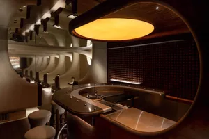 A warm and inviting restaurant bar with a counter and stools, surrounded by chairs and a comfortable atmosphere