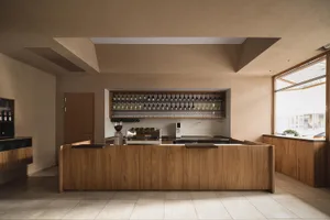 A restaurant bar area with wooden floors and walls, featuring bottles on the countertop, creating a warm and welcoming atmosphere for socializing and dining