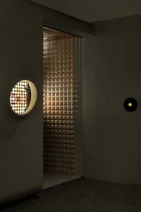 Dimly lit hallway with a tile wall, two side lights, and a doorway leading to another room