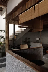 Cozy home interior with a staircase, two chairs, a potted plant, and a vase, featuring a warm and inviting atmosphere