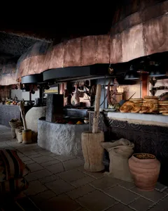 A traditional European-style kitchen with a rustic atmosphere, featuring various food items, bowls, bottles, and apples on tables and counters