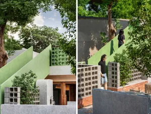 Modern house with concrete walls and flooring, featuring a green door and a person walking down steps near a tree in a natural setting
