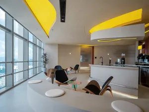 Open living area with white walls and floors, featuring a dining table, chairs, a potted plant, and decorative vase