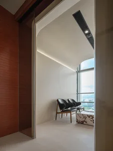 A modern living area with a large window, two black chairs, and a couch, featuring neutral colors and sleek lines
