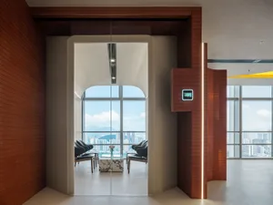An open living area with a cozy seating arrangement, dining table, and natural light from a glass door leading to a balcony with a city skyline view