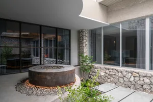 Cozy indoor space with a stone wall, fireplace, windows, and potted plants