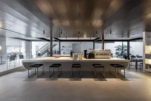 Industrial kitchen with a countertop bar area, white walls, silver fixtures, and potted plants