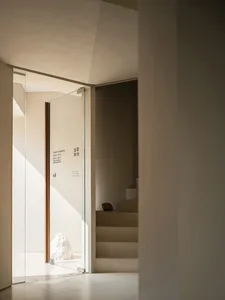Industrial style hallway with concrete walls, glass door, and staircase, conveying a sense of depth and organization