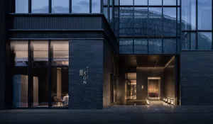 A modern glass building at night with a spacious interior, featuring chairs and dining tables, and a contemporary atmosphere