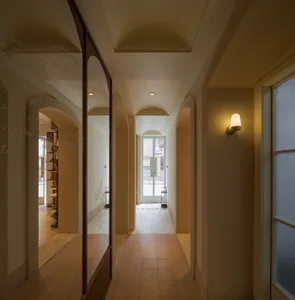 A modern hallway with a mirror and door, featuring a clean and modern look with tiled flooring and books placed along the space