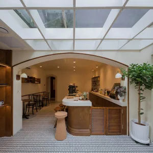 Inviting restaurant kitchen with a dining area, countertop, sink, dining table, chairs, potted plants, and bottles on display