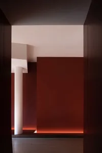 Narrow hallway with red walls and white columns, giving a dark and empty atmosphere