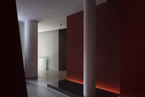 A calm and serene interior hallway with red walls, white columns, and a bench, giving a sense of grandeur
