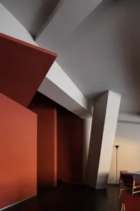 Empty minimalist room with red walls and white ceilings, featuring two large pillars on either side