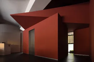 A large, empty room with red walls and an open door, featuring a modern design and bold red paint