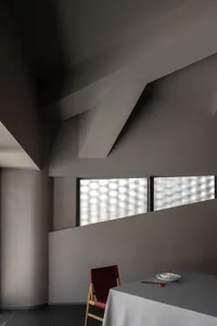 Interior view of a modern house with concrete walls, two windows, and a focus on design elements
