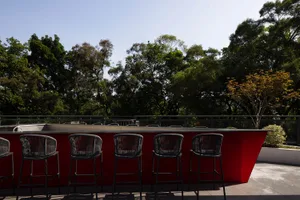 A modern outdoor patio area with a metal bar counter and stools, surrounded by trees and providing a relaxing atmosphere