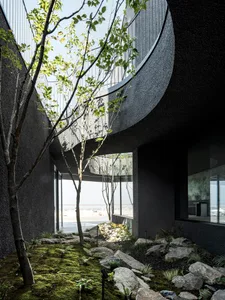 Modern house with a black exterior, spiral staircase, and a balcony on the second floor, surrounded by trees