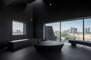 A spacious bathroom with a round stone bathtub, two windows, and a bench near one of the windows