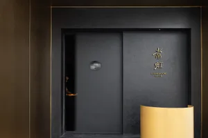 A dark entrance with a black door, two people standing in front, and an air of mystery