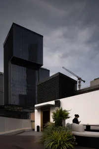 A bustling city scene with a modern building and two people walking in the foreground, set against a backdrop of impressive architecture