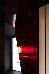 A modern entrance with a red glass door in front of a window, surrounded by a bright and airy space