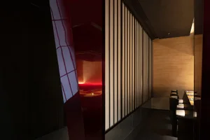 Dining area with a red accent wall, wooden door, and two chairs, creating a warm and inviting atmosphere