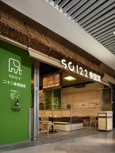 A modern Asian restaurant with a thatched roof and green exterior, featuring dining tables and chairs in a comfortable atmosphere