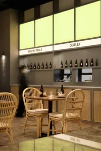 A cozy restaurant dining area with wicker chairs, tables, and bottles, set in a warm and inviting atmosphere