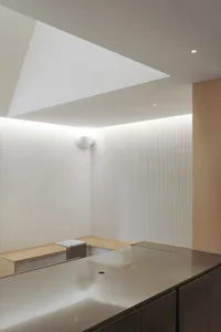 Empty minimalist kitchen with white walls, a wooden countertop, and two benches on either side