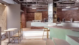 Warm and inviting restaurant interior with a large brick wall, wooden door, and multiple dining tables and chairs