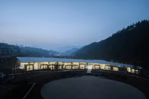 A modern building with a circular shape and lit windows, set against a dark background