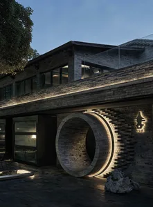 A modern house with a brick exterior, featuring a circular design element and warm lighting that highlights the brickwork and architectural details