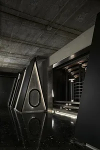 Industrial space with a black and white color scheme, featuring three large metal triangular structures and a minimalist atmosphere