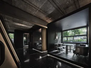 Modern open-plan living space with a black and white color scheme, featuring a dining area, living room, and potted plants, with a sleek and contemporary feel