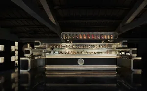 A sophisticated bar with a large display of liquor bottles on a counter, accompanied by wine glasses, suggesting a high-end establishment or luxury hotel