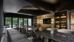 Sophisticated living space with a black marble table, chairs, and a mounted TV, surrounded by wine glasses