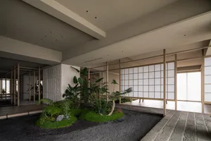 A serene indoor space with potted plants and benches, surrounded by lush greenery and natural materials