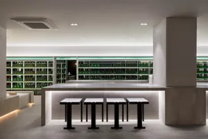A luxurious bar area with a marble counter, stools, and bottles on display in a sophisticated and inviting environment