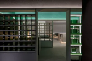 Modern kitchen with white walls, green accents, and a functional layout featuring a sink, oven, and refrigerator, with scattered bottles adding a personal touch