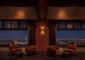 Comfortable living area with two orange chairs, three couches, and natural light from a window