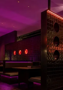 Modern restaurant interior with a purple accent wall, black tile flooring, and unique red circle designs on the walls