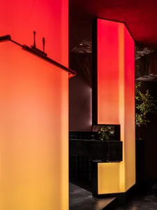 A warm and inviting bathroom with orange and yellow walls, a black countertop, and a red-hued sink area