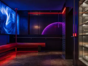 A modern lounge area with two red benches, one large and one small, surrounded by black walls, creating a sleek and contemporary look