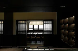 Dark dining space with wooden floors and walls, featuring chairs and tables arranged in a restaurant setting