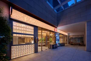 A modern Asian restaurant with a glass facade, minimalist decor, and natural light pouring in through the large window