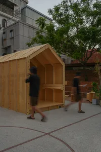 A wooden building with a large doorway, surrounded by people walking past, with a sense of exploration and discovery